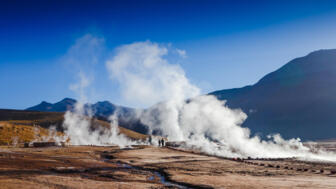 Besucher vor dampfenden Geysiren auf dem Vulkanfeld El Tatio am Rande der Atacama-Wüste in Chile