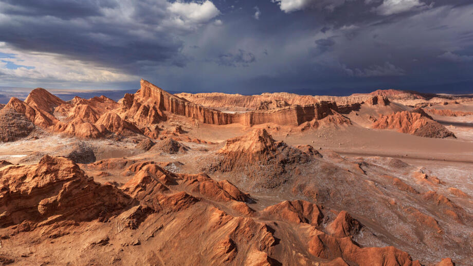 Valle de La Luna mit bizarren Gesteinsformationen in rotem Sonnenlicht mit schwarzen Wolken