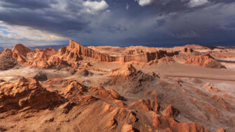 Valle de La Luna mit bizarren Gesteinsformationen in rotem Sonnenlicht mit schwarzen Wolken