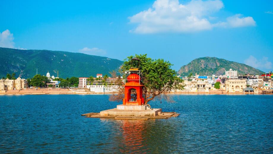 Der Pushkar-See in Rajasthan wird von einem kleinen Hindu-Tempel auf einer Insel geschmückt. Die malerische Kulisse mit See, Stadt und Bergen macht Pushkar zu einem bedeutenden Pilgerort in Indien.