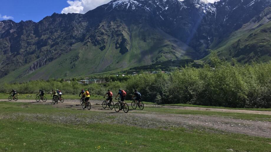 Eine Mountainbikegruppe unterwegs im Kaukasus. Im Hintergrund ist die Bergwelt zu sehen.