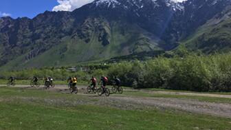 Eine Mountainbikegruppe unterwegs im Kaukasus. Im Hintergrund ist die Bergwelt zu sehen.