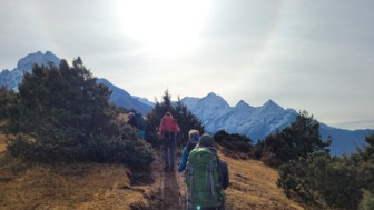 Eine Gruppe Wanderer auf einem Pfad mit Blick auf schneebedeckte Gipfel im Hintergrund