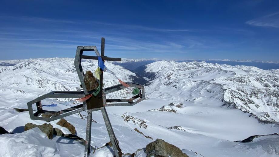 Gipfelkreuz mit blauem Himmel und Bergpanorama